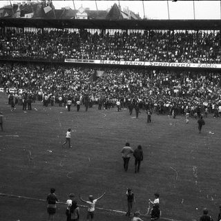Massive stadium crowd during chaotic post-match scene.