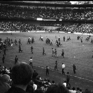 Extra-time soccer match with chaotic crowd on field.