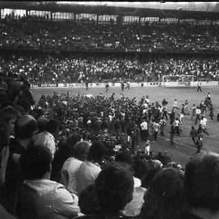 Historic soccer match with chaotic crowd and players.