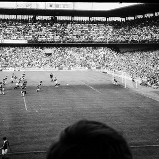 Black-and-white soccer match with packed stadium.
