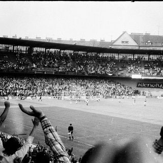 Black-and-white stadium crowd celebrating soccer match.