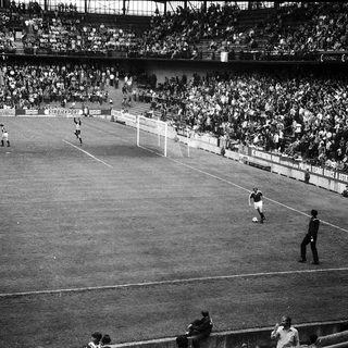 Black-and-white soccer match with packed stadium.