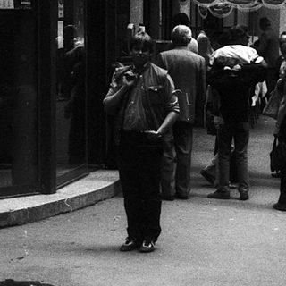 Crowded street scene with people queuing outside a store.