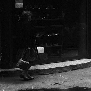 Crowded street scene with people queuing outside a store.