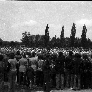 Large crowd gathered outdoors in solemn assembly.
