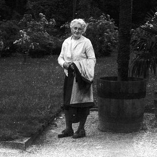 Woman standing alone in a garden at dusk.