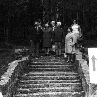Group posing on stone steps near forest sign.