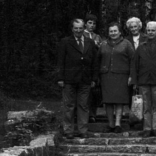 Group posing on stone steps near forest sign.
