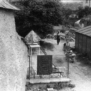 Urban courtyard with small structures, people, and enclosed birdcage area.