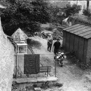 Rural courtyard with people, shed, and old lantern.