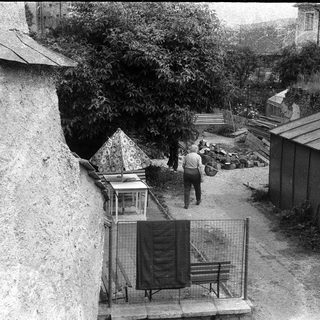 Urban courtyard with man walking near shed and benches.