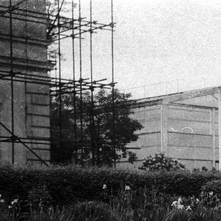 Large greenhouse with people standing outside.