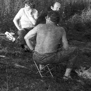 People preparing and cooking meat outdoors.