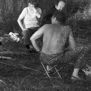 Group preparing outdoor meal with butchered animal.