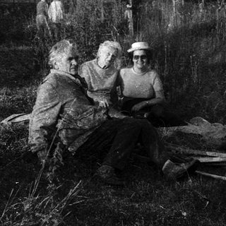 Group of people resting outdoors in rural field.
