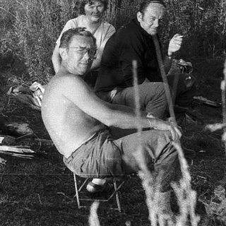 Group of people resting outdoors near a campfire.