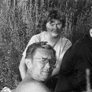 Group of people resting outdoors near a campfire.