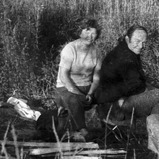Group of people relaxing by a lake.