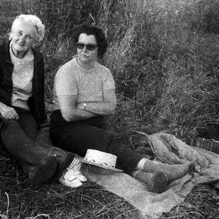 Two women and a German Shepherd in outdoor setting.