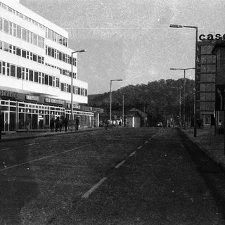 Empty urban street with mid-century buildings and railway tracks.