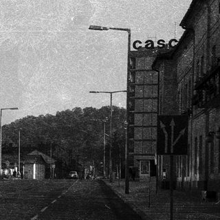 Empty urban street with mid-century buildings and railway tracks.