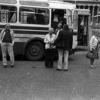 People boarding a vintage bus at a bus stop.