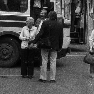 People boarding a vintage bus at a bus stop.