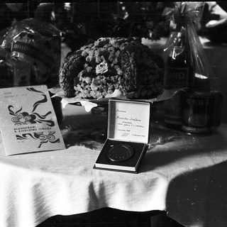 Vintage table display with cake, boxed chocolates, and medal box.