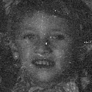 Child holding illuminated lantern in dark setting.