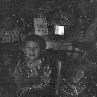 Child holding illuminated lantern in dark setting.