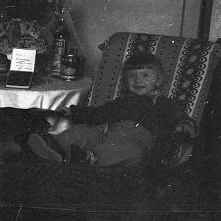 Black-and-white photo of person reading at small table.