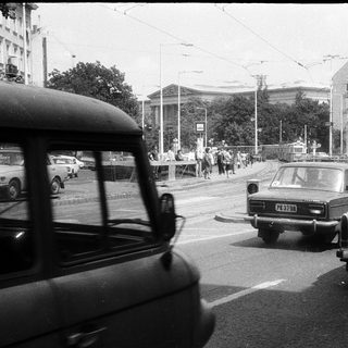 Urban street scene with vintage cars and pedestrians.