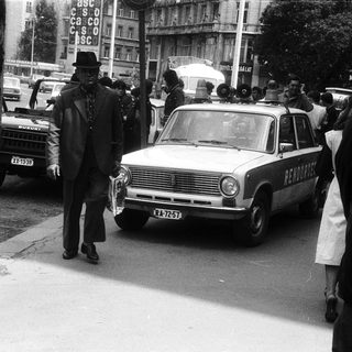 Vintage funeral procession with hearse and mourners.