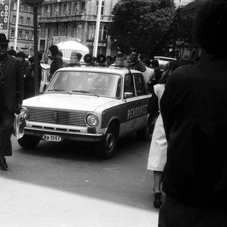 Vintage funeral procession with hearse and mourners.