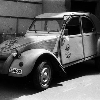 Classic Citroën 2CV with vintage decals parked.