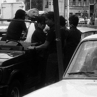 Police checkpoint with SUV and civilians stopped.