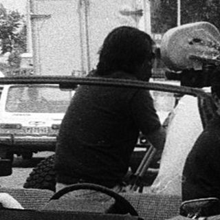 Police checkpoint with SUV and civilians stopped.