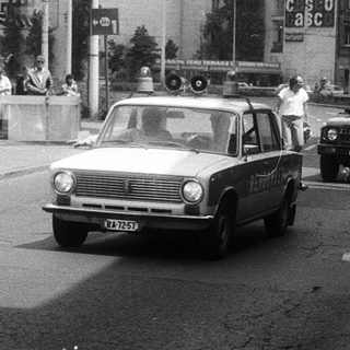 Urban street scene with police cars, crowd, and protest signs.