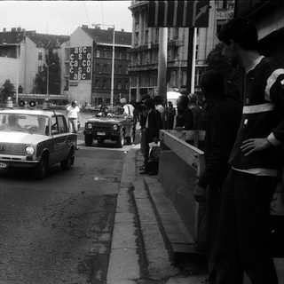 Urban street scene with police cars, crowd, and protest signs.