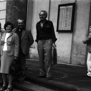 Five adults posing together outdoors in formal attire.