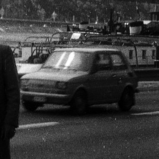Man standing near bridge with statue on hill.