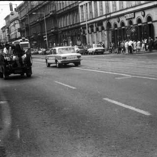 Urban street scene with vintage vehicles and pedestrians.