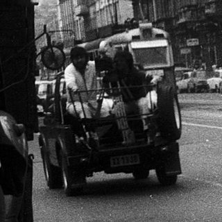 Urban street scene with vintage vehicles and pedestrians.