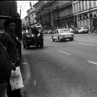 Urban street scene with vintage vehicles and pedestrians.