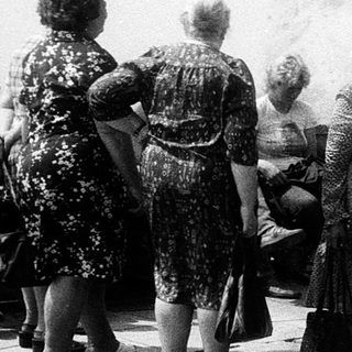 Group of people standing outdoors in line.