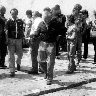 Group of people standing outdoors in line.