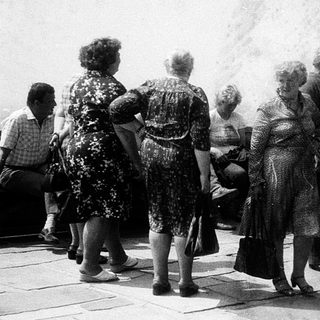 Group of people standing outdoors in line.