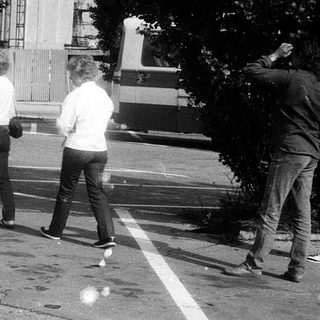 Group of people playing frisbee near parked bus.