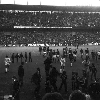 Massive stadium crowd after soccer match. Players on field.