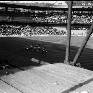 Black-and-white stadium scene of a cycling race.